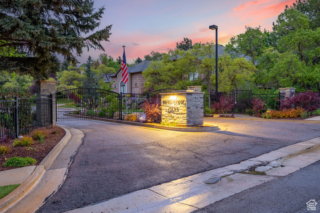 View of road featuring street lights, a gated entry, a gate, and curbs