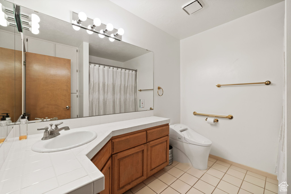 Full bathroom with toilet, baseboards, visible vents, tile patterned flooring, and vanity