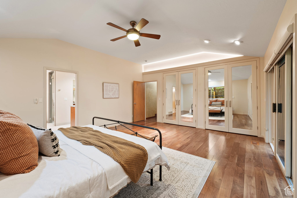 Bedroom with a ceiling fan, french doors, ensuite bathroom, vaulted ceiling, and light wood-style floors