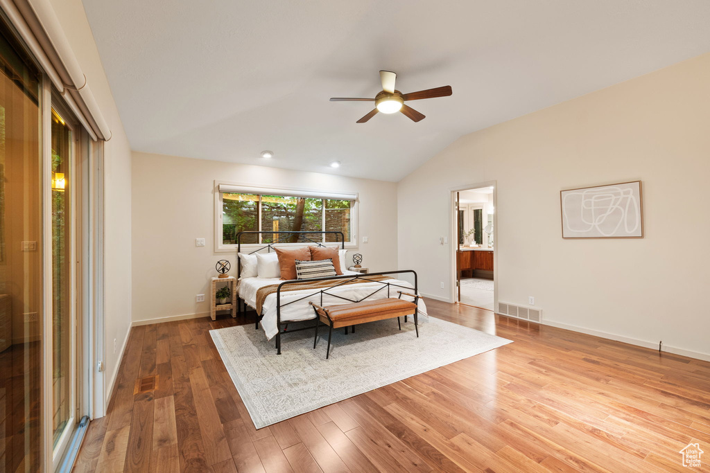 Bedroom with lofted ceiling, baseboards, visible vents, connected bathroom, and hardwood / wood-style flooring