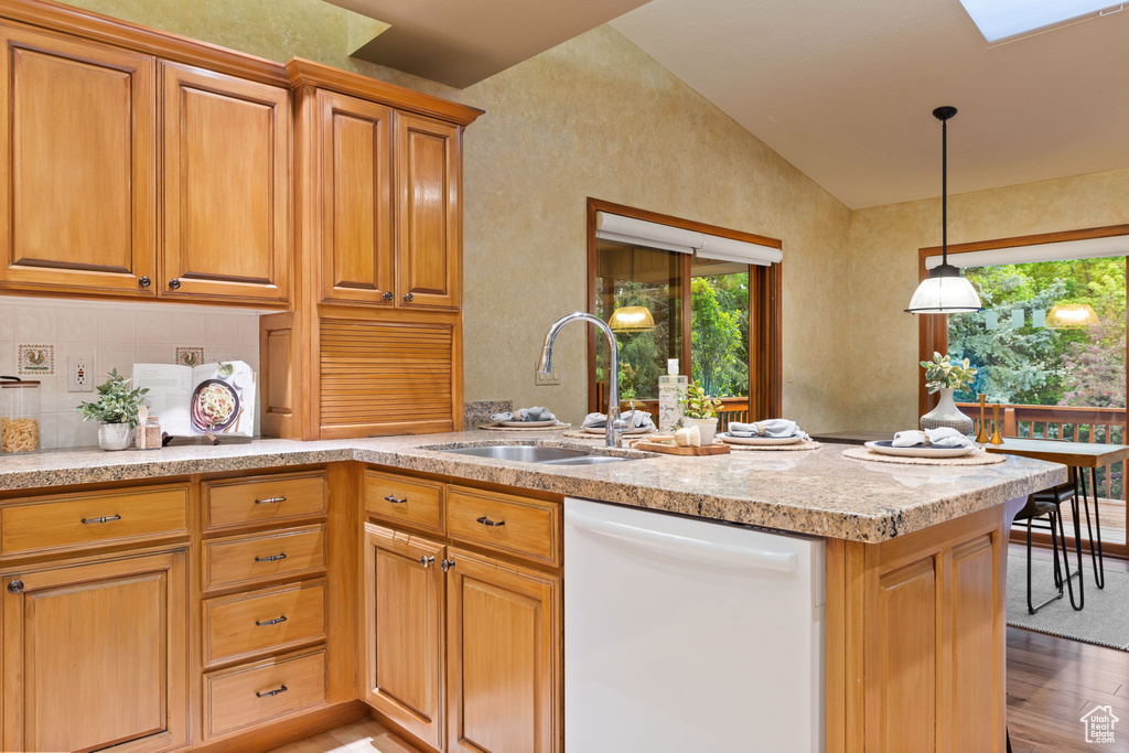 Kitchen with white dishwasher, light wood-style flooring, lofted ceiling with skylight, a sink, and a peninsula