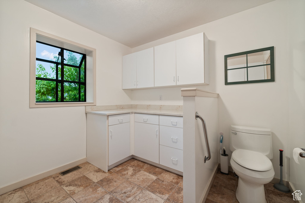 Bathroom with baseboards, stone finish floors, toilet, and vanity