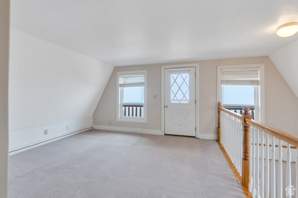 Additional living space featuring vaulted ceiling, light carpet, and baseboards