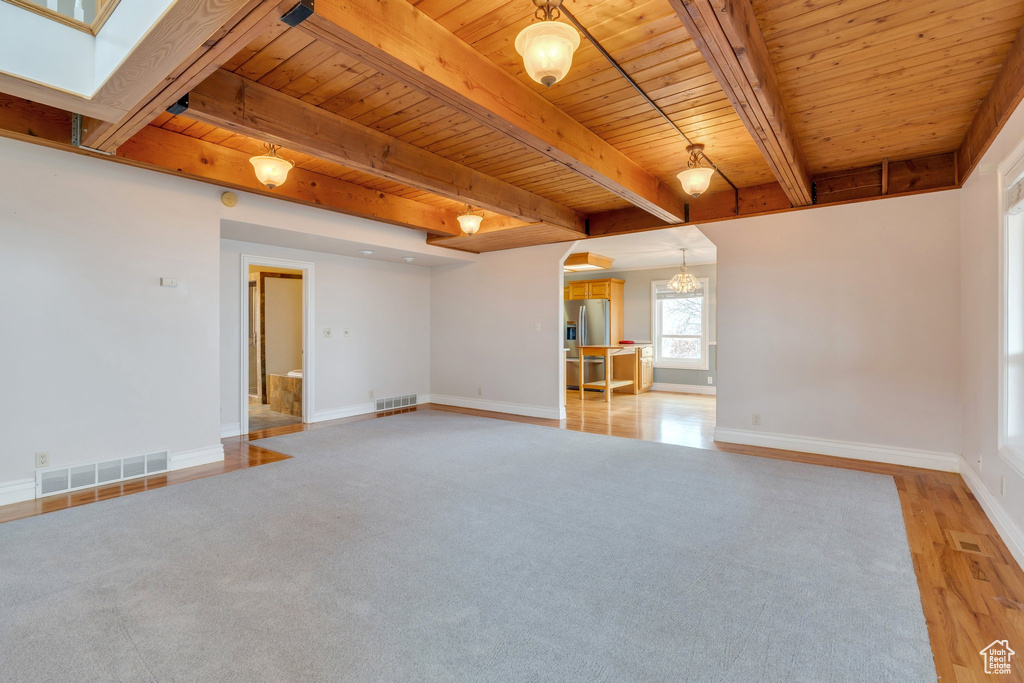 Unfurnished living room featuring wood ceiling, arched walkways, baseboards, light wood-type flooring, and beam ceiling