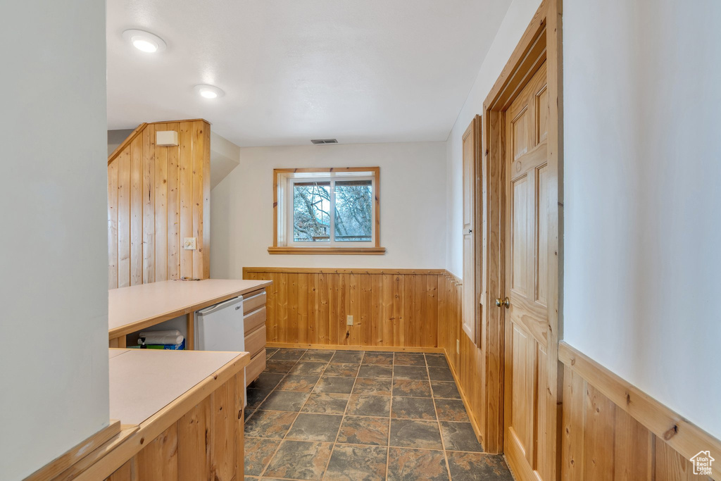 Additional living space featuring stone finish flooring, wooden walls, and a wainscoted wall