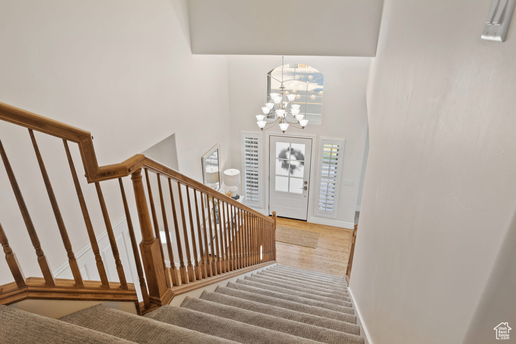 Foyer entrance featuring stairs, a chandelier, baseboards, a towering ceiling, and wood finished floors