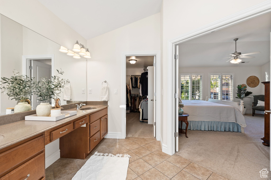 Bathroom with a ceiling fan, connected bathroom, tile patterned flooring, vanity, and high vaulted ceiling