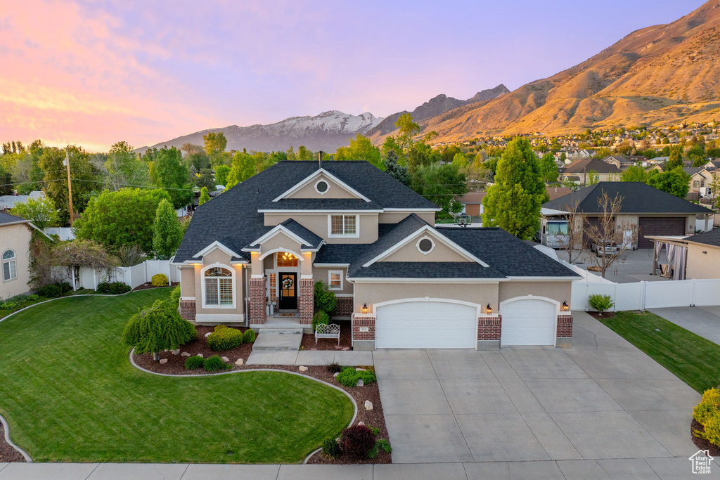 View of front of property with brick siding, a garage, driveway, and a mountain view