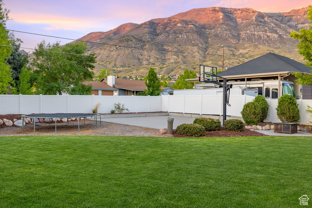Yard at dusk featuring a mountain view, a trampoline, and a gazebo