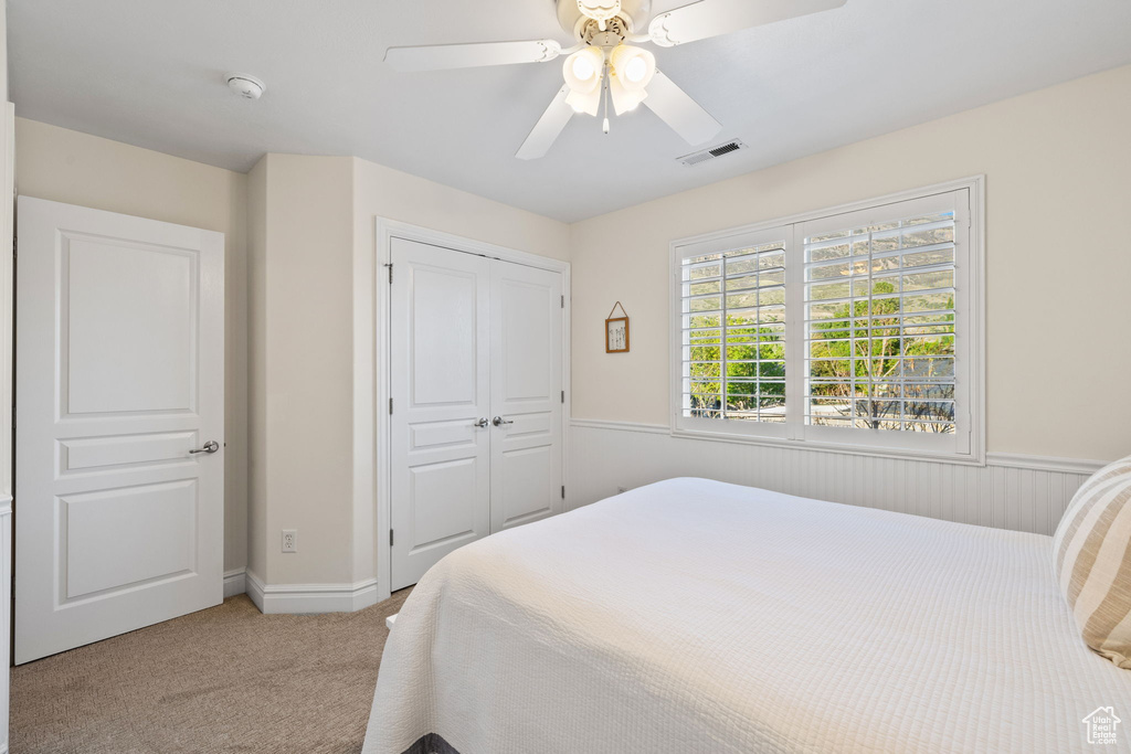Bedroom featuring light colored carpet, a closet, ceiling fan, and baseboards