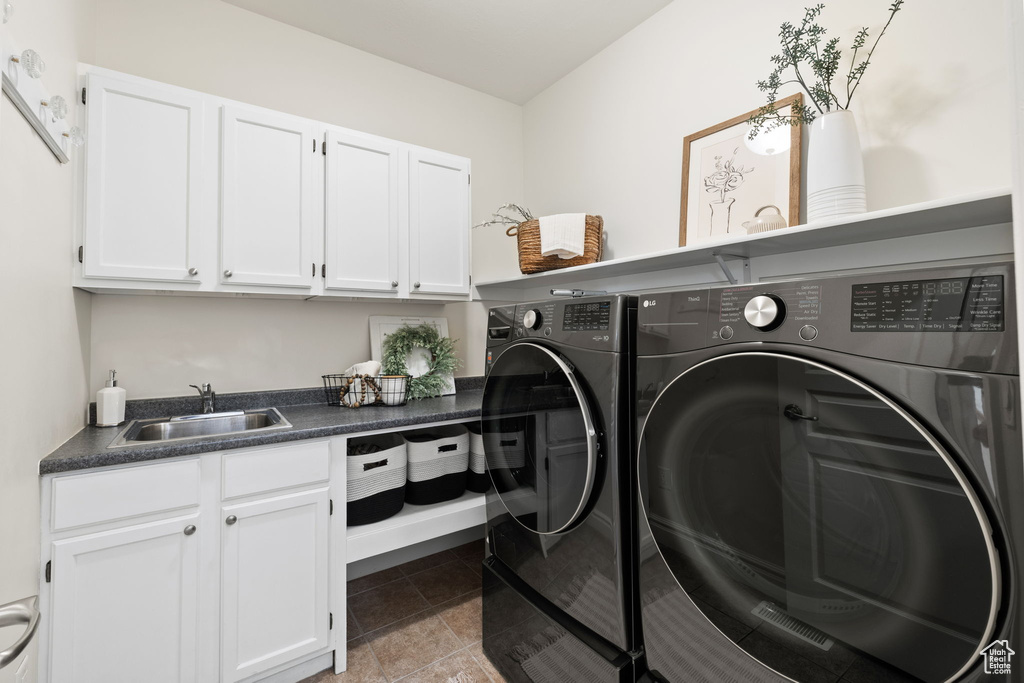 Clothes washing area featuring independent washer and dryer, cabinet space, and light tile patterned floors