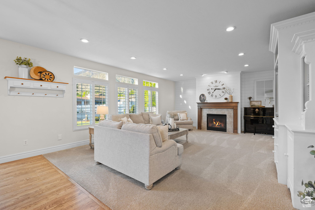 Living room with recessed lighting, a tile fireplace, baseboards, light colored carpet, and light wood finished floors