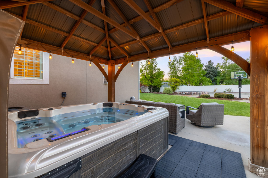 Patio terrace at dusk featuring a gazebo and a hot tub