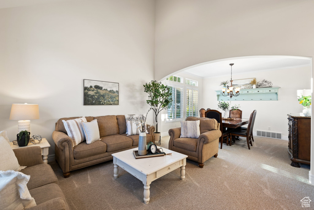 Living area featuring arched walkways, a chandelier, carpet floors, and baseboards