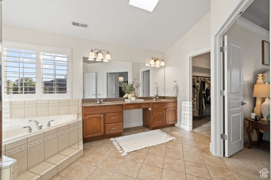 Full bathroom featuring tile patterned flooring, a bath, vanity, a walk in closet, and a skylight