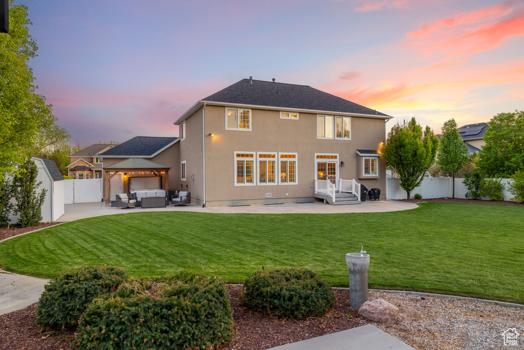 Back of property at dusk with outdoor lounge area, a patio, a gazebo, and stucco siding