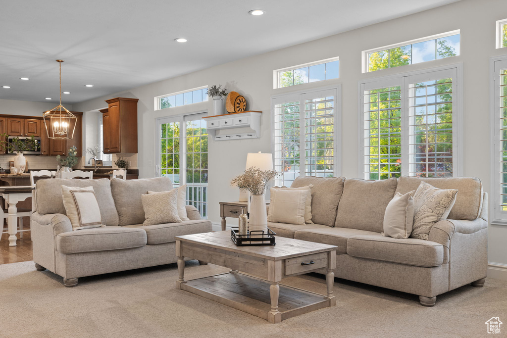 Living area with recessed lighting, a chandelier, and light colored carpet