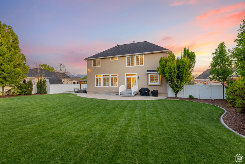 Back of house at dusk with a patio area, a gate, stucco siding, an outdoor structure, and entry steps