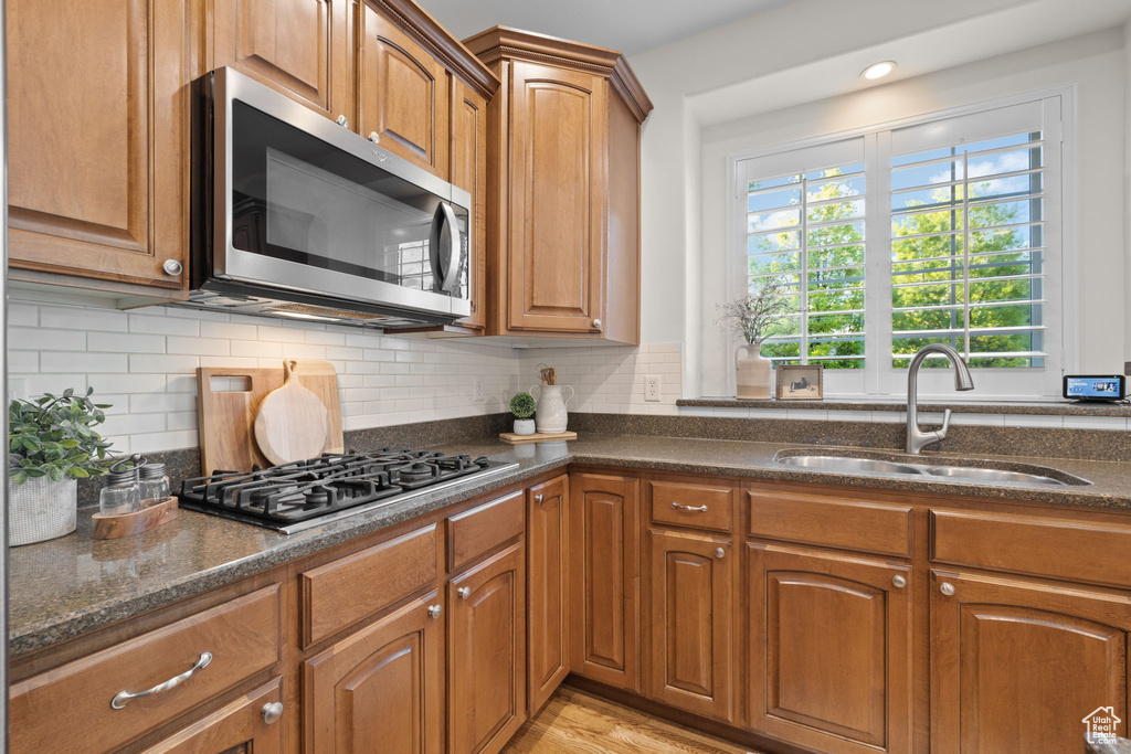 Kitchen featuring stainless steel microwave, a sink, gas stovetop, and dark stone countertops