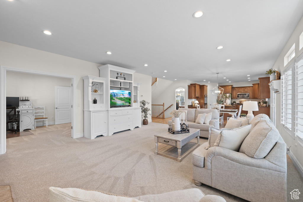 Living area with recessed lighting, plenty of natural light, light colored carpet, and baseboards