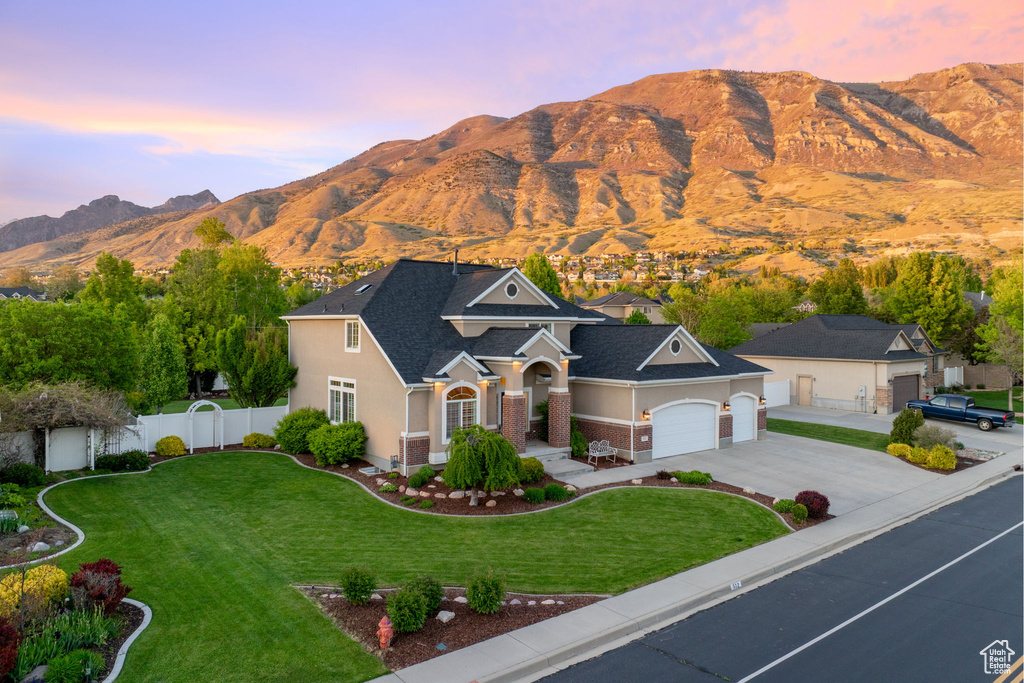 View of front of home featuring a mountain view, driveway, a garage, roof with shingles, and stucco siding