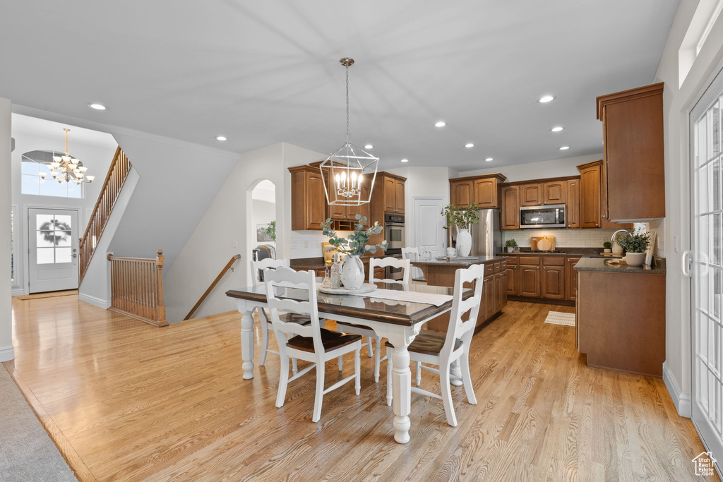 Dining space featuring a chandelier, recessed lighting, light wood finished floors, arched walkways, and stairs