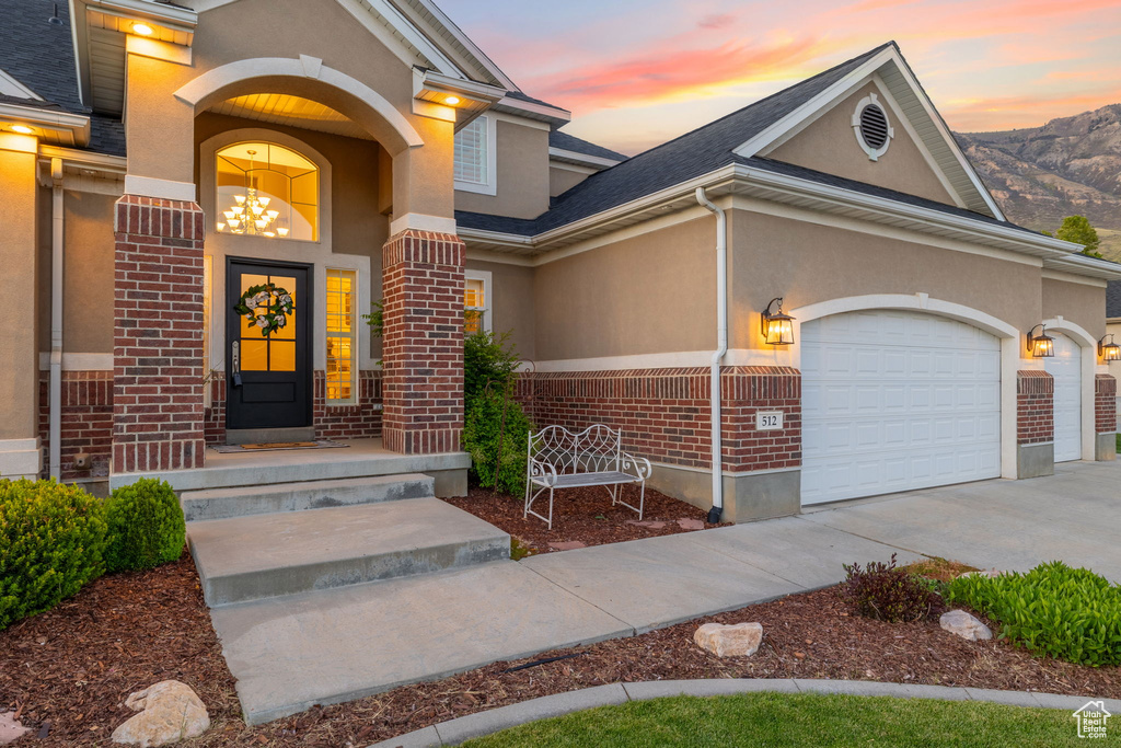 View of front facade with brick siding, stucco siding, driveway, and an attached garage