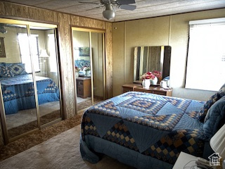 Bedroom with carpet flooring, multiple closets, and wood walls
