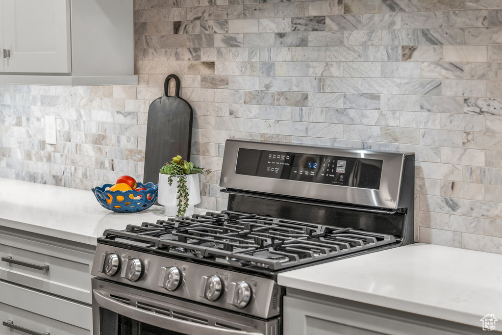 Kitchen view of gas range, backsplash, and light countertops