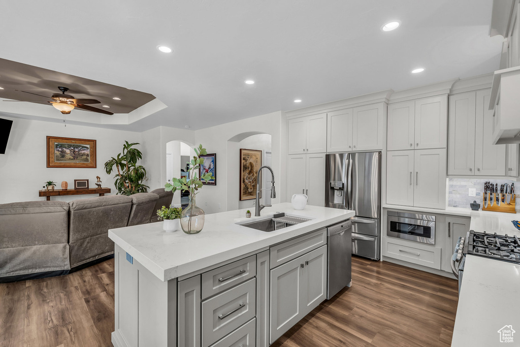 Kitchen featuring arched walkways, appliances with stainless steel finishes, a sink, open floor plan, and recessed lighting