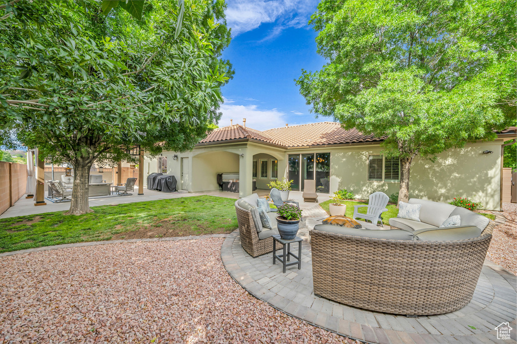 Rear view of house featuring stucco siding, an outdoor hangout area, a tiled roof, fence, and a patio
