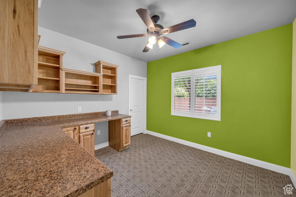 Kitchen with open shelves, ceiling fan, baseboards, tile patterned floors, and built in desk