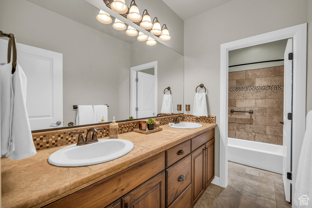 Full bath featuring double vanity,  shower combination, and stone finish floors