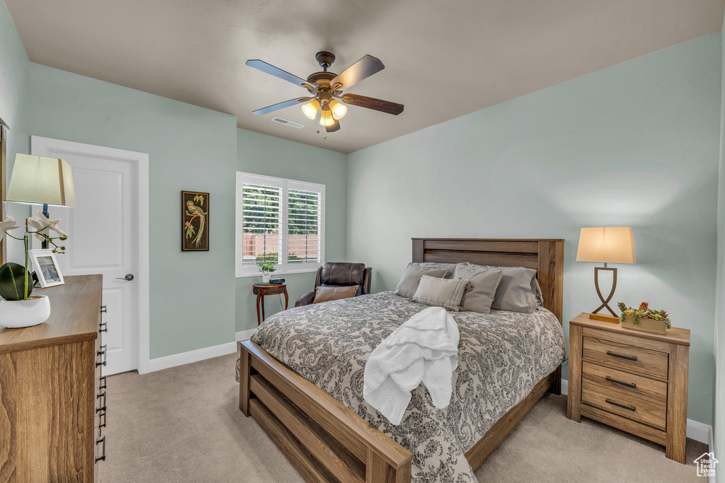Bedroom with light colored carpet, baseboards, and a ceiling fan