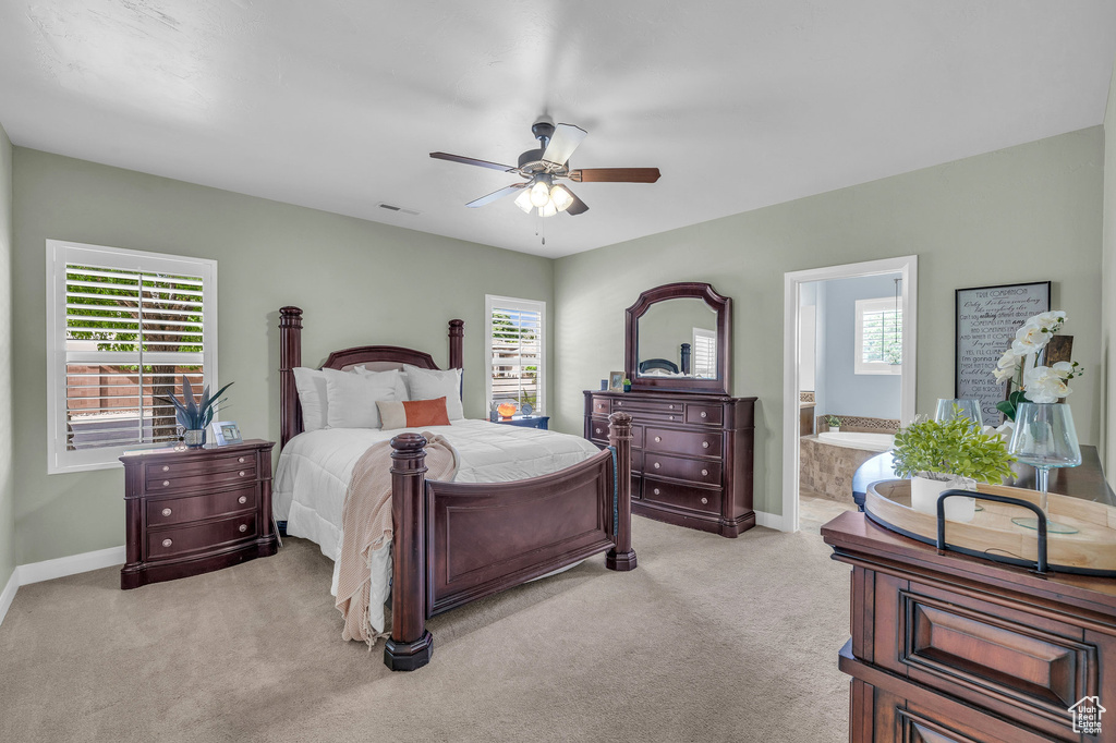 Bedroom with multiple windows, light carpet, and baseboards