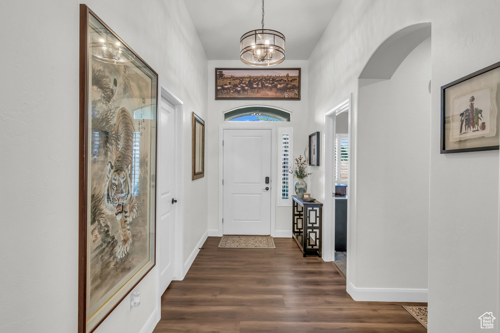 Entrance foyer featuring dark wood finished floors, a chandelier, baseboards, and arched walkways