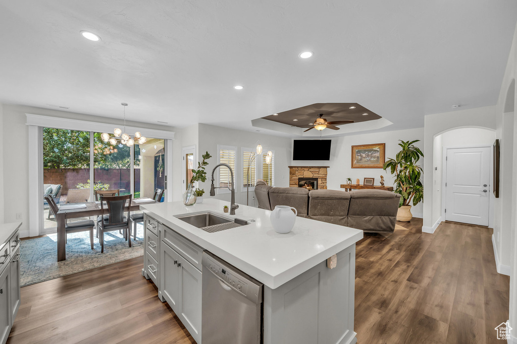 Kitchen featuring stainless steel dishwasher, a stone fireplace, light countertops, a chandelier, and recessed lighting
