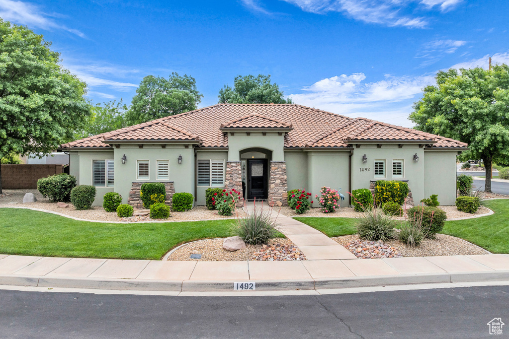 Mediterranean / spanish home with stucco siding, a tile roof, and stone siding
