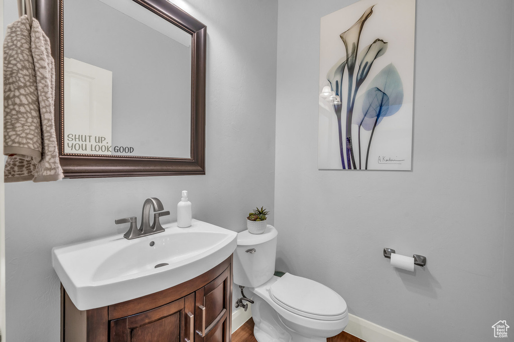 Bathroom with toilet, vanity, and baseboards