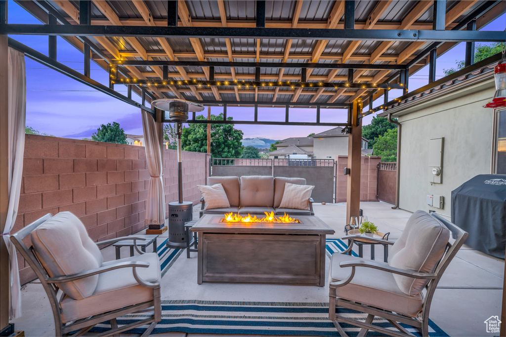 Patio terrace at dusk featuring a fire pit, a fenced backyard, and a grill