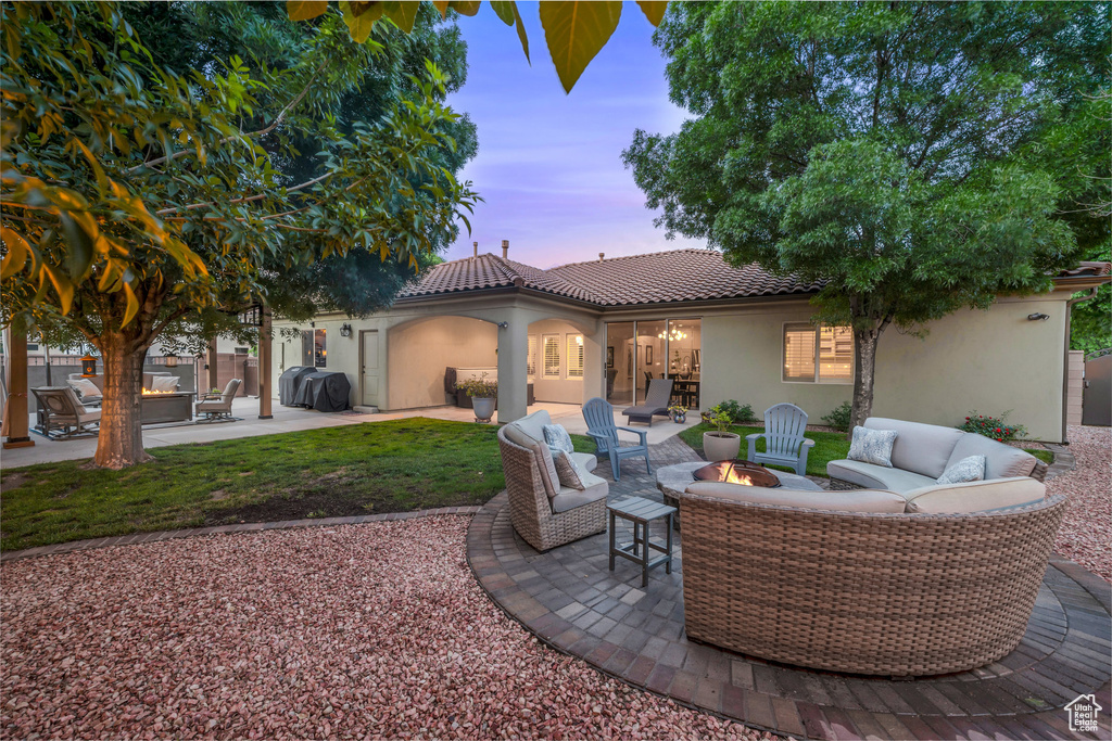Patio terrace at dusk with an outdoor living space with a fire pit