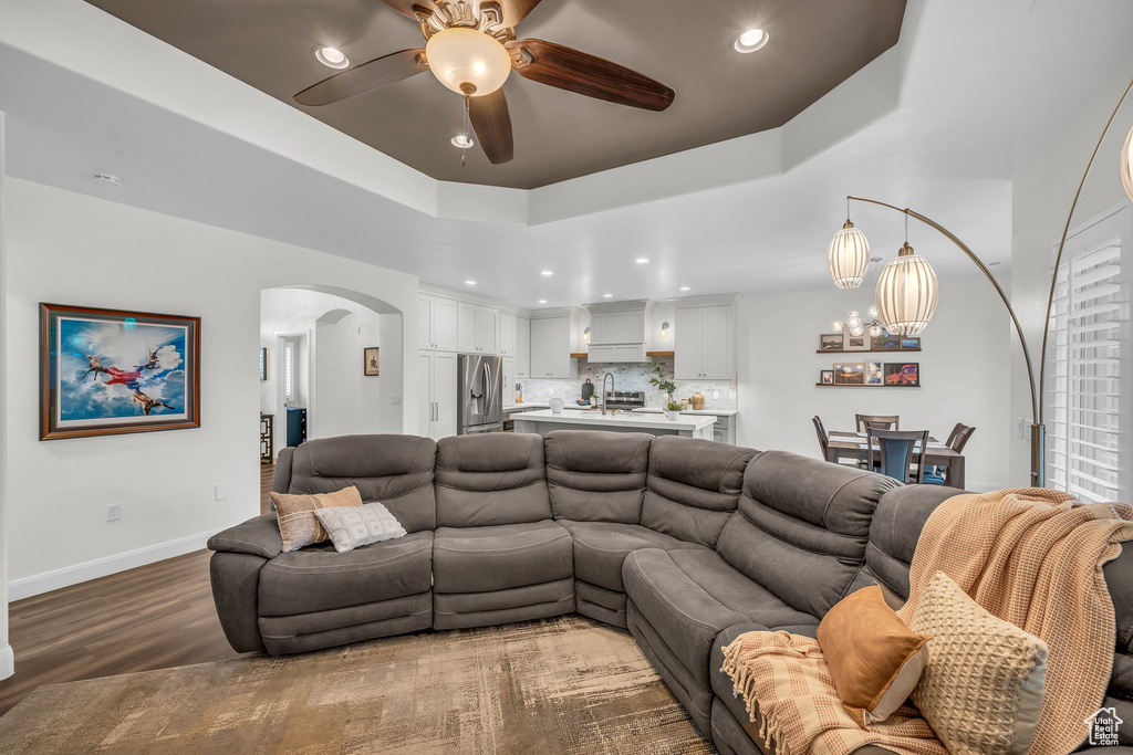 Living area with arched walkways, wood finished floors, ceiling fan, recessed lighting, and baseboards