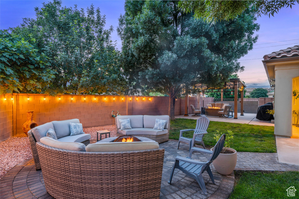 Patio terrace at dusk featuring an outdoor living space with a fire pit, a fenced backyard, and a pergola
