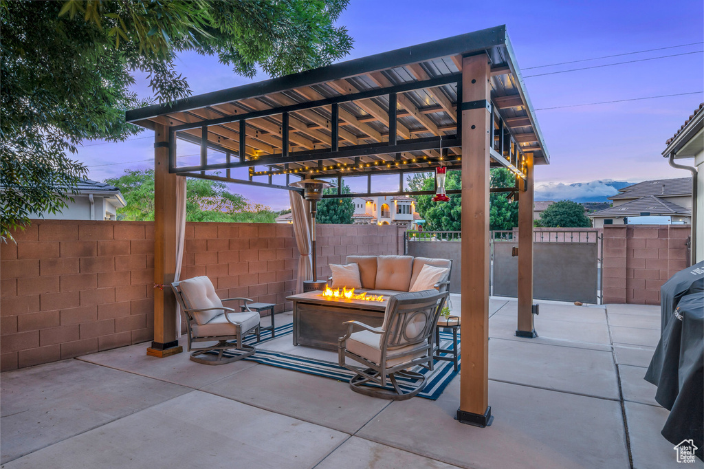 Patio terrace at dusk with a fire pit and fence