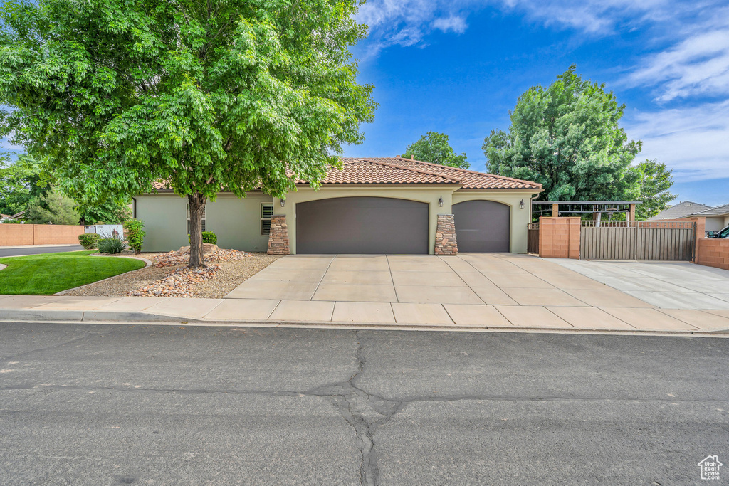 View of front of house featuring stucco siding, a garage, driveway, fence, and a tile roof