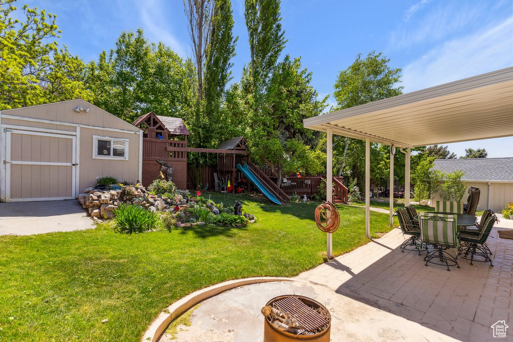 View of yard with a patio, a playground, a shed, an outdoor structure, and outdoor dining space