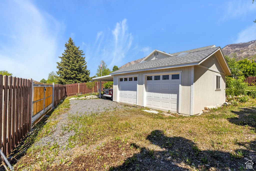 View of property exterior featuring a fenced backyard, roof with shingles, and a detached garage