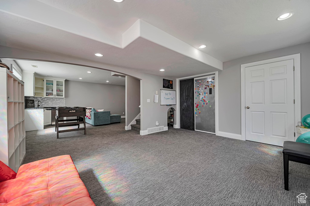 Living area with dark carpet, recessed lighting, stairway, and baseboards