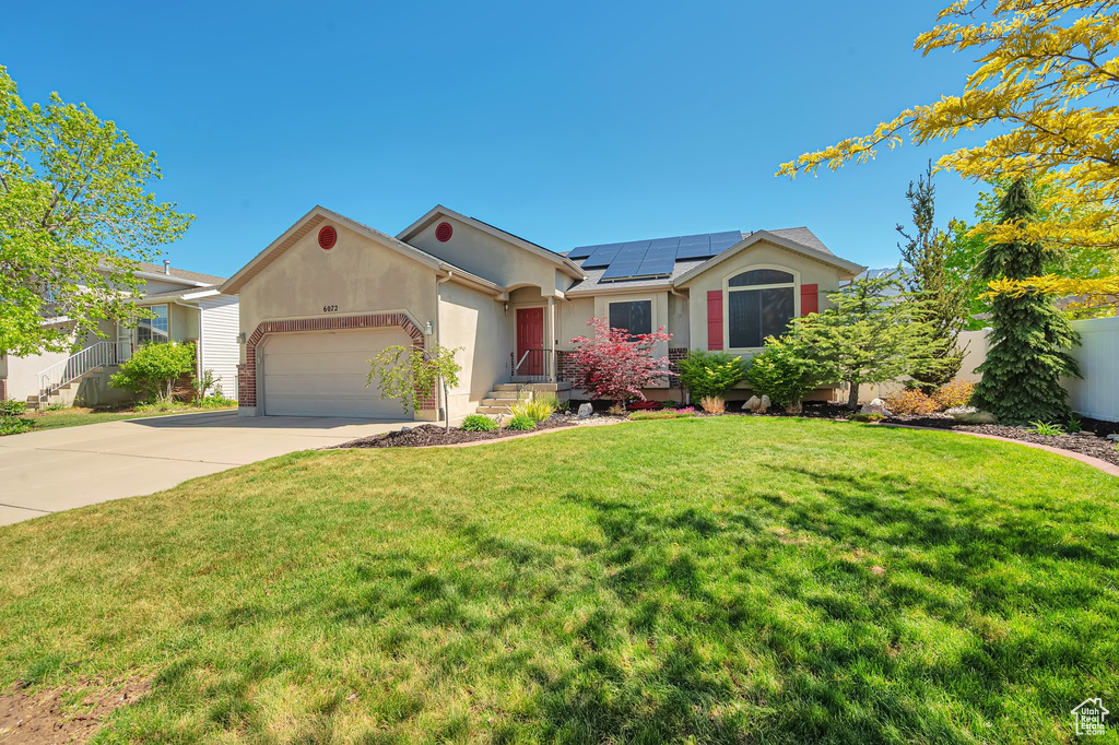 Single story home with stucco siding, solar panels, concrete driveway, and a garage