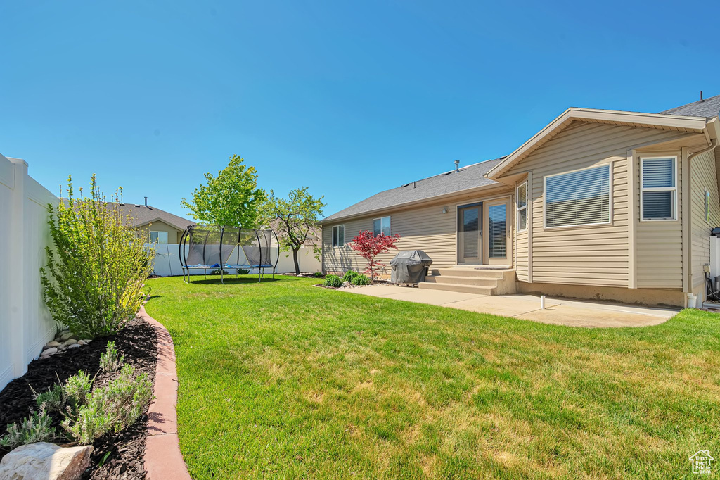 Rear view of property featuring a trampoline, a patio area, and entry steps